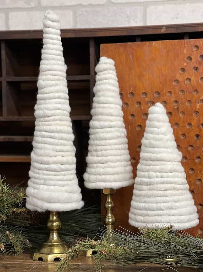 Finished wool trees on brass candlestick holders as bases.