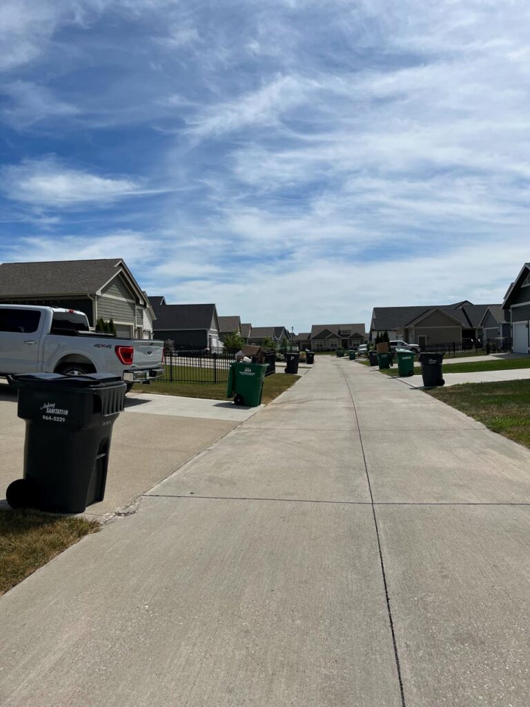 View of the alley which is how all homes enter their garages.  Also shows trash cans and recycling bins ready to be picked up. the Junk Parlor