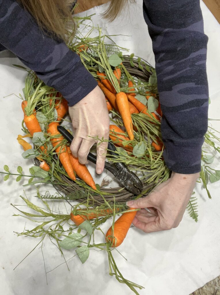 I'm using wire cutters/pliers to remove the carrot stems from the grapevine wreath.