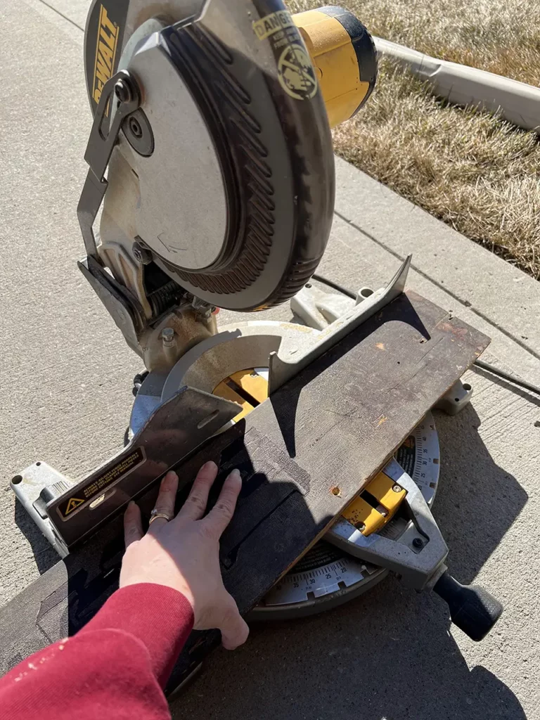 Cutting the extra board off of the end of the sign using a chop saw