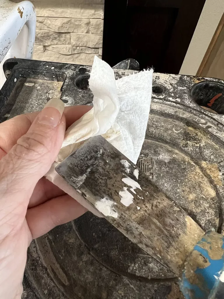 wiping off dried filler from the putty knife with a damp paper towel