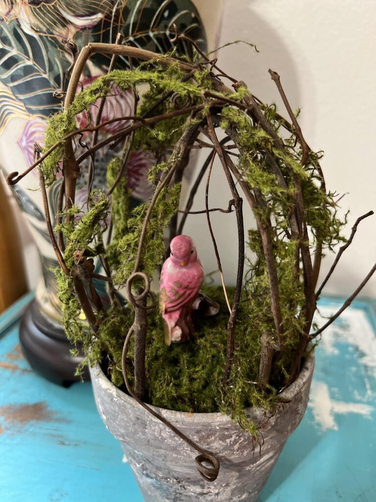 vintage ceramic bird inside a moss covered topiary
