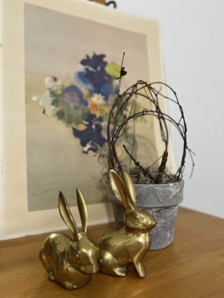 brass bunnies in front of a floral print and topiary