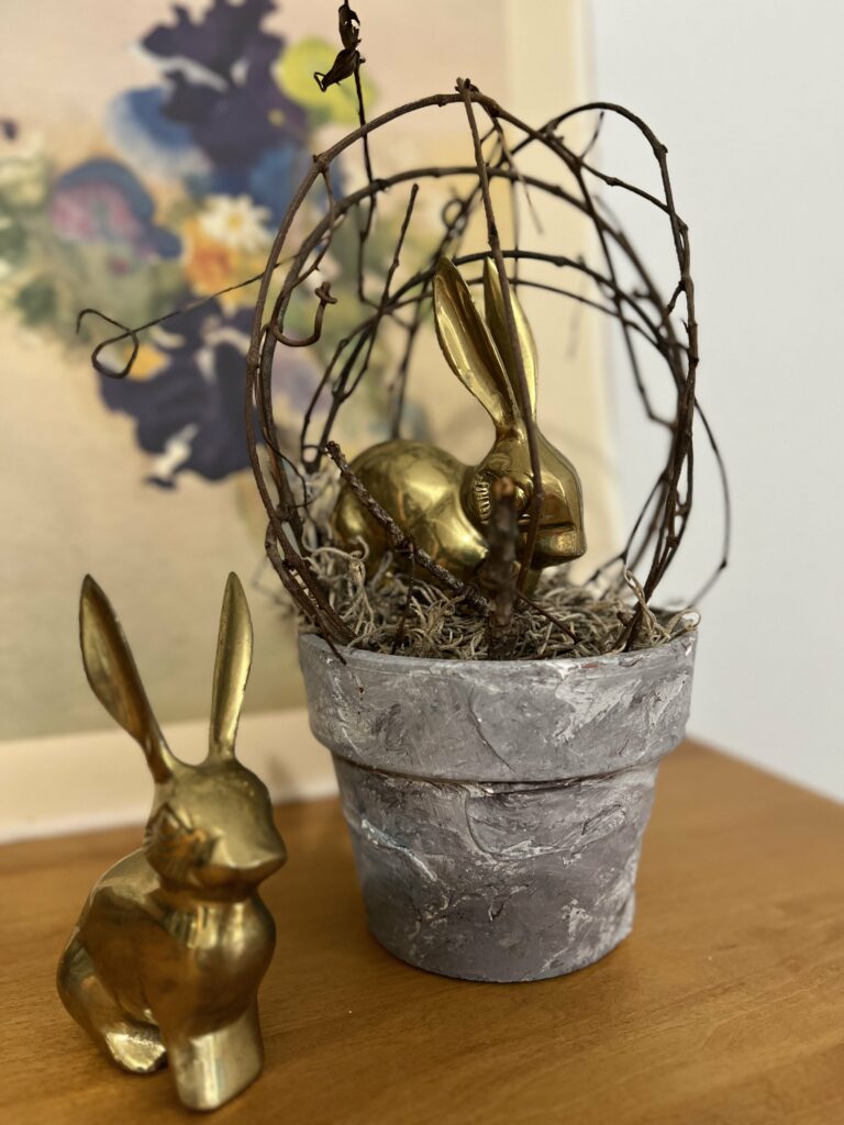 vintage brass bunnies in front of and inside a topiary with a floral print in back