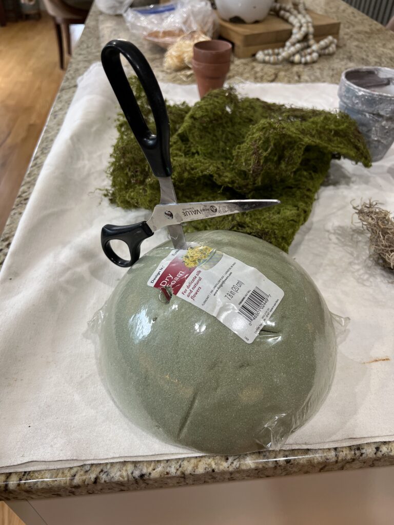 dry foam half sphere shaped being stabbed/cut with scissors