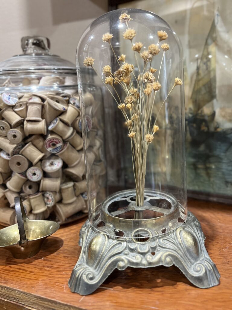 Dried flowers in a lamp base with a cloche on top