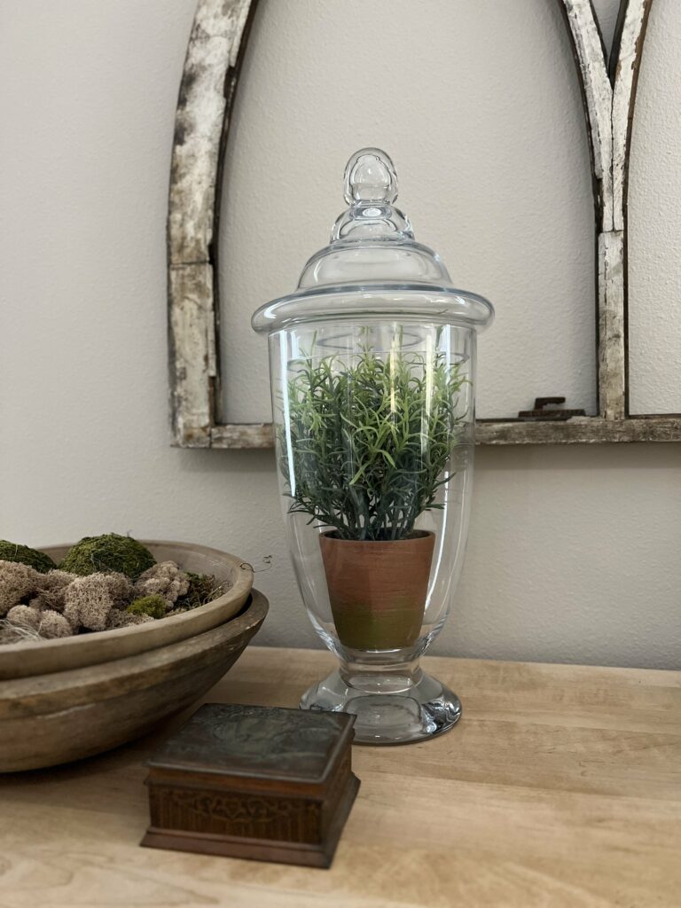 Apothecary jar with a faux plant.