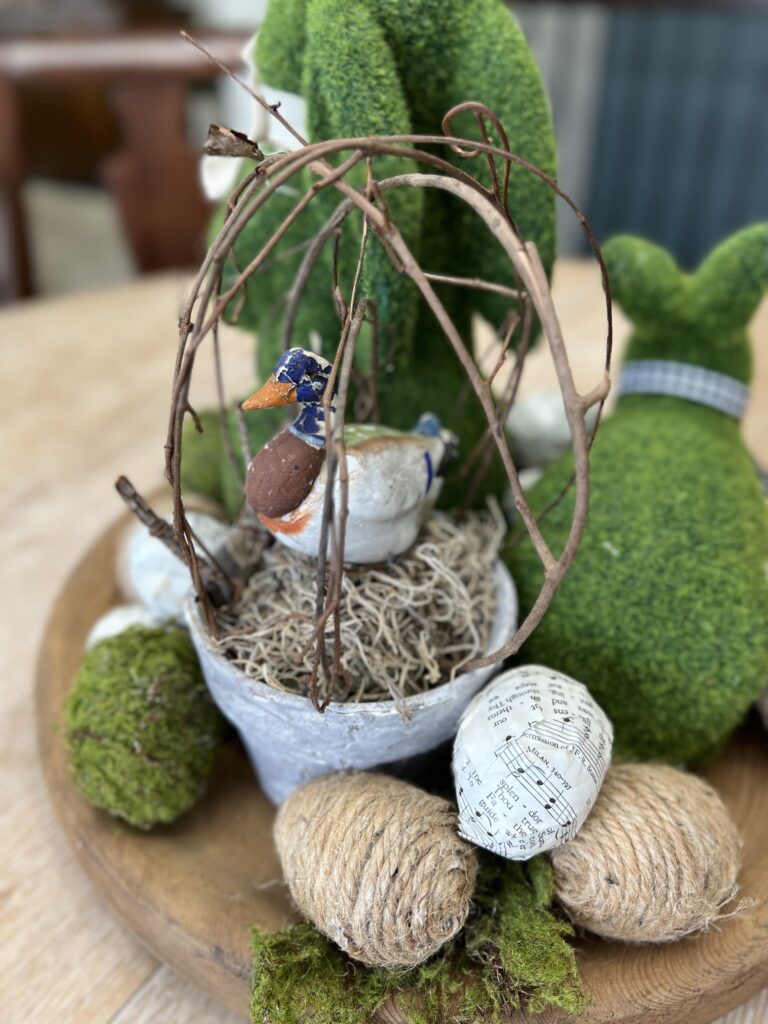 up close shot of a grapevine topiary with a antique paper mache candy duck inside.
