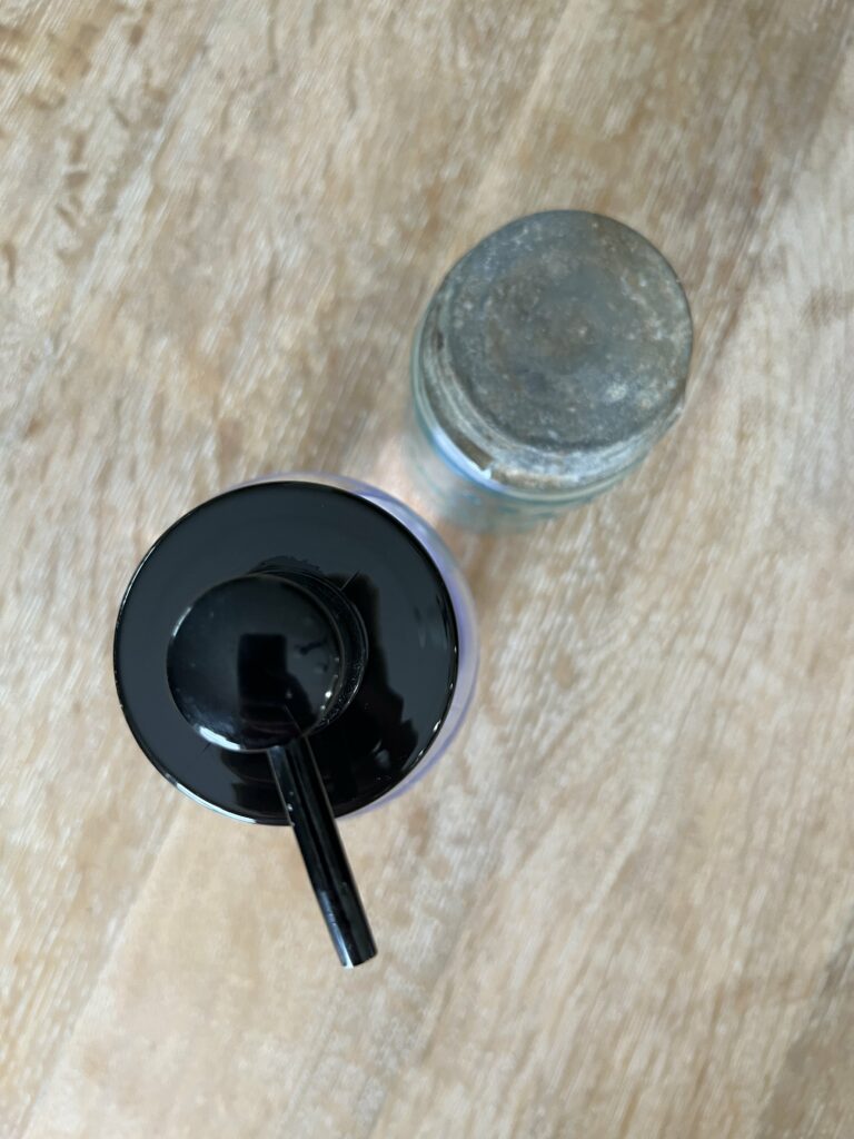 Birds eye view of a new dispenser lid and an antique jar lid