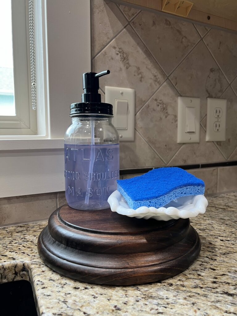 Repurposed mason jar into soap dispenser sitting on a riser at the sink
