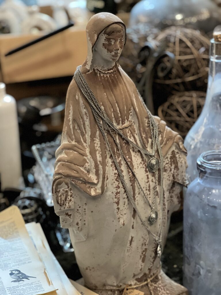 concrete Mary with rosaries layered on her