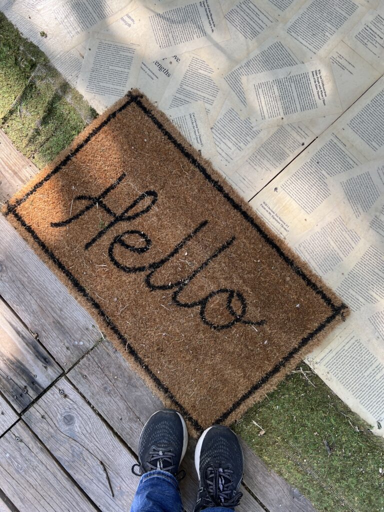 Welcome mat that says hello and a floor of decoupaged book pages