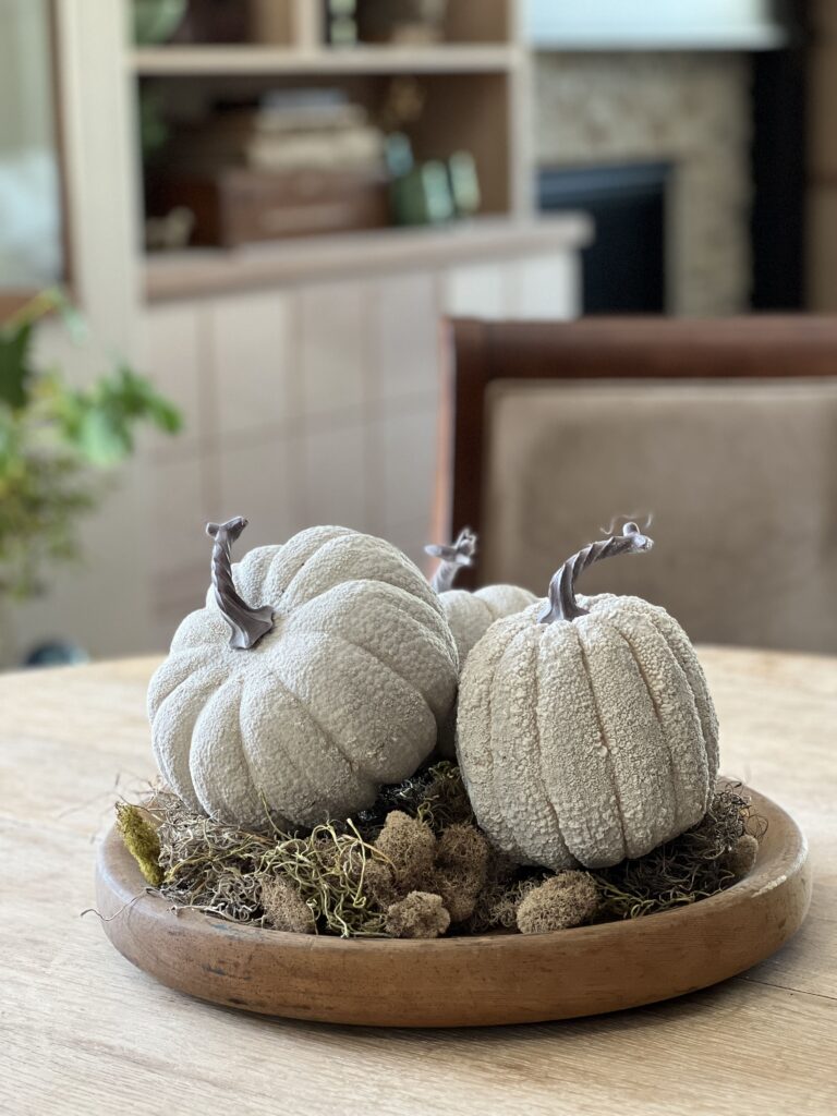 pumpkins and moss on a round bread board