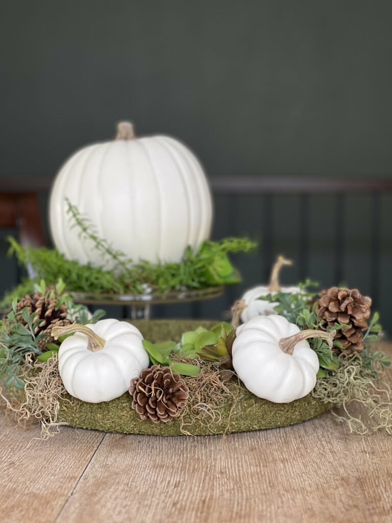 pumpkin and succulent wreath as a centerpiece with another pumpkin on a cake stand
