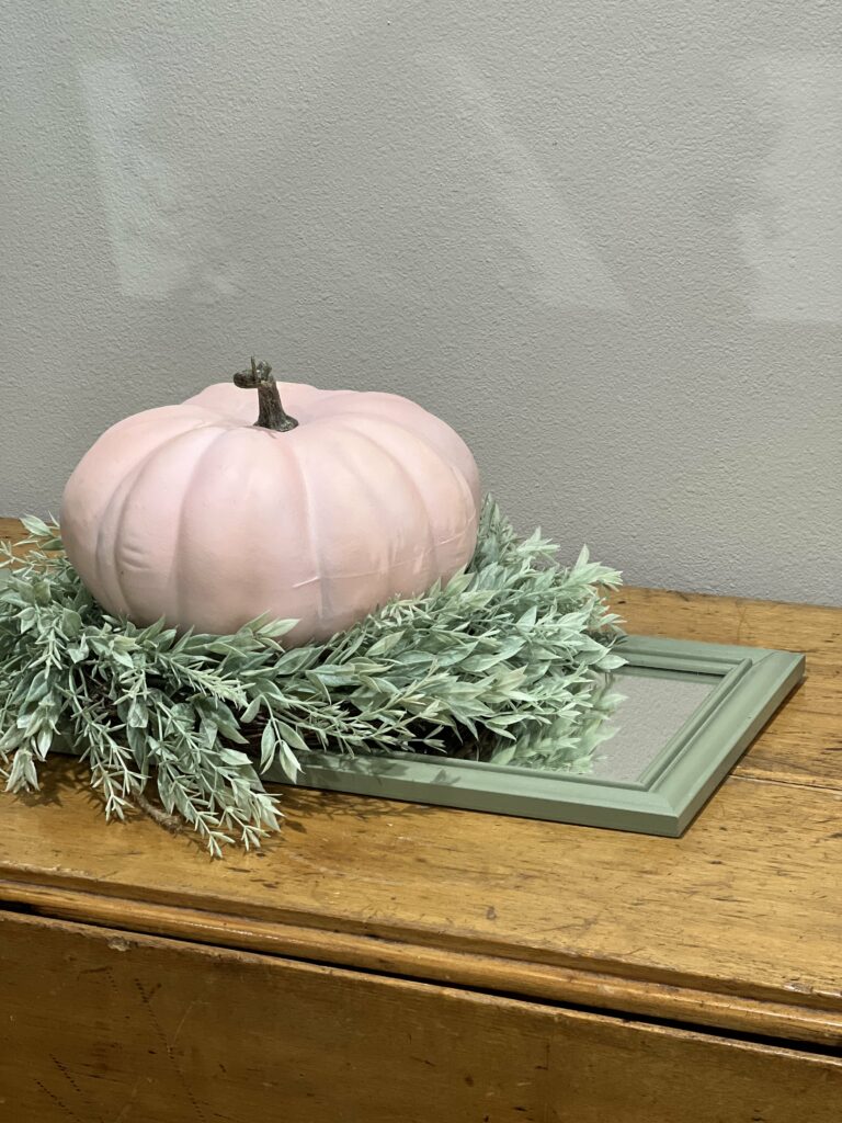 A mirror with a wreath and pumpkin on it.