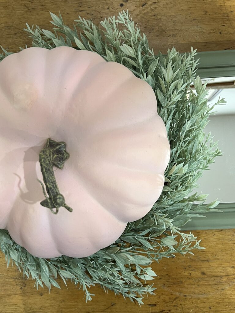 A mirror with a wreath and pumpkin on it.